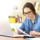 Une femme devant son PC avec une calculette