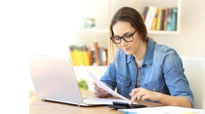 Une femme devant son PC avec une calculette