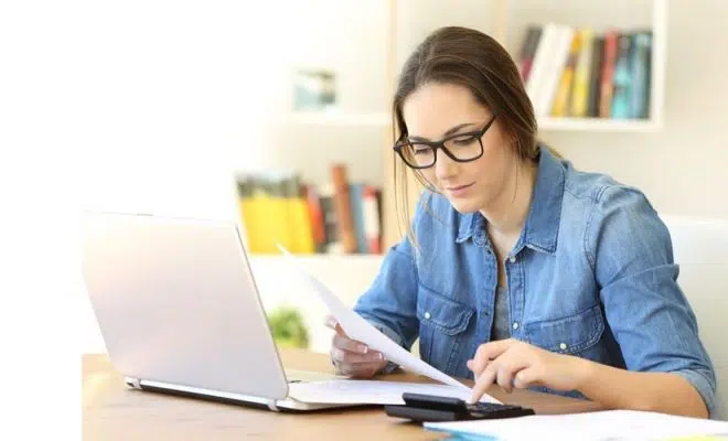 Une femme devant son PC avec une calculette