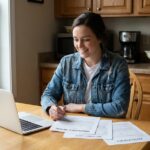 Jeune femme souriante avec ordinateur et devis d'assurance