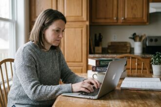 Femme concentrée travaillant sur son ordinateur dans la cuisine