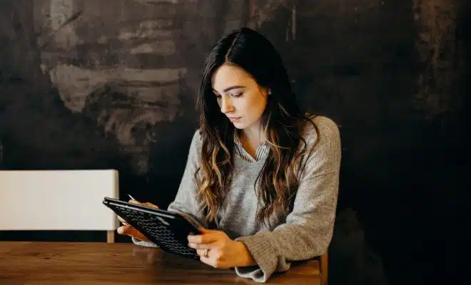 woman wearing white dress shirt using holding black leather case on brown wooden table